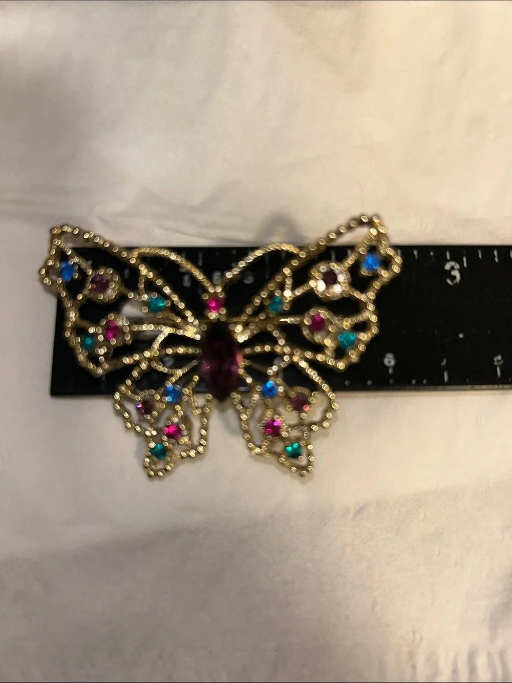 Dodds filigree butterfly brooch featuring a large amethyst-colored center stone